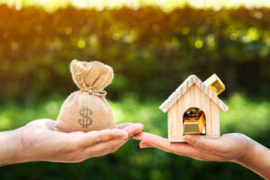 Man and women hand hold a home and a money bag